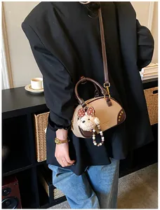 Detail of vintage beige suede boston bag with plush bear charm and side rivet accents