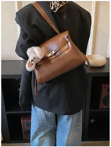 Close-up of vintage brown leather shoulder bag with metallic buckle and plush charm detail