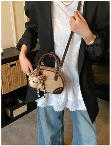 Detail of vintage color-block suede bag with plush bear charm and metallic rivets