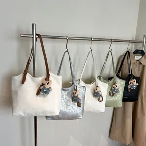 Large vintage tote bags in white silver and black with teddy bear charms on metal rack