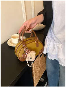 Detail view of mustard yellow vintage mini Boston bag with plush bear charm and metal rivets