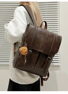 Detail view of a vintage dark brown leather backpack with decorative buckle straps and plush charm