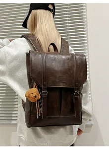 Detailed back view of a vintage faux leather backpack with metallic buckle and bear charm