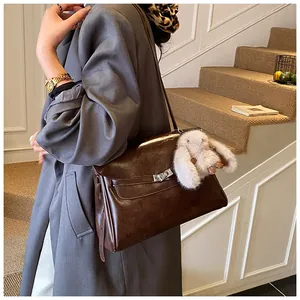 Detail of dark brown leather shoulder bag with silver twist lock and cute bunny pendant