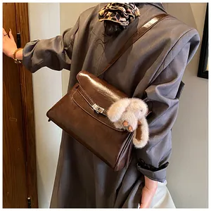 Detail view of glossy brown vintage faux leather shoulder bag with plush bunny charm