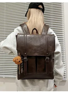 Detail of vintage brown faux leather backpack with twin straps and plush bear charm