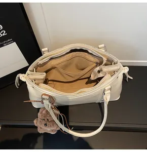 Detail view of large tote bag interior showing brown lining and zip pocket with bear charm