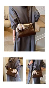 Detail of vintage brown glossy shoulder bag with silver clasp and plush rabbit charm