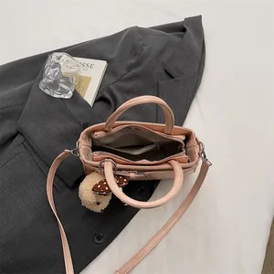 Borsa in pelle rosa con tracolla e ciondolo a pecora su giacca da abito grigia elegante