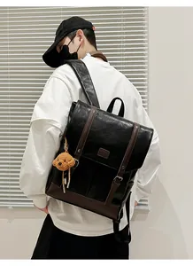 Detail of vintage faux leather backpack featuring embossed logo and brown plush bear charm