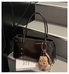 Detail of dark brown glossy leather tote with silver studs and a plush dog charm