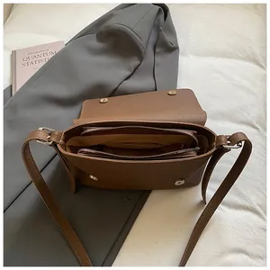 Détail du sac marron en cuir grainé avec double fermeture éclair et fermoir magnétique