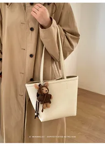 Detailed view of the off-white lychee grain tote bag with a cute brown teddy bear charm