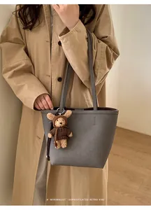 Close-up of a grey litchi grain tote bag with a cute brown knit bear charm accessory