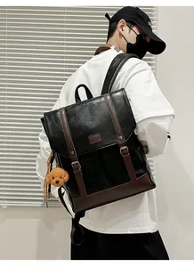 Detail of black pebbled leather backpack with brown trim and cute teddy bear charm accessory