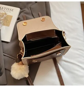 Detail view of the retro crossbody bag's interior, double magnetic buckles, and plush charm