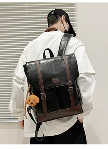 Side view of black matte leather backpack with brown straps and cute plush dog pendant