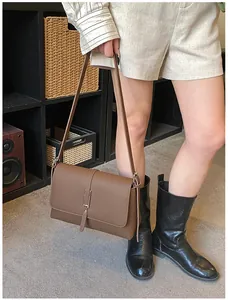 Détail de la texture motif litchi marron et de la boucle argentée sur le sac à main