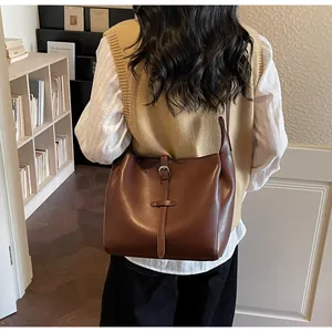 Detail of dark brown vintage faux leather hobo bag worn crossbody in a cozy library