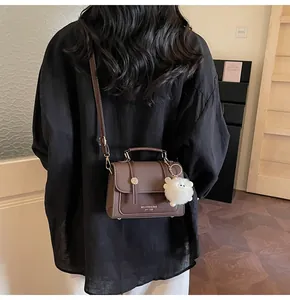 Rear view of model carrying a retro brown patchwork shoulder bag with plush pendant