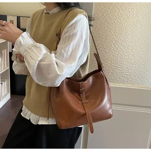 Detailed view of vintage brown leather handbag with buckle strap on a model