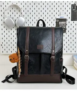 Close-up of black pebble grain leather backpack with brown straps and plush dog charm