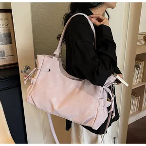 Detail of pink tote bag showing the textured synthetic leather and drawstring side accents