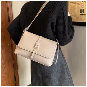 Détail d'un sac bandoulière beige en cuir grainé porté par un mannequin en style rétro
