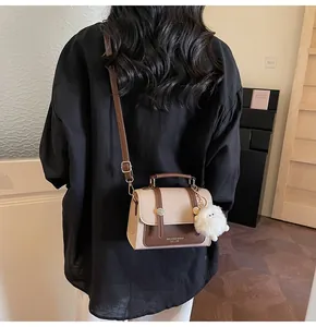 Detail of vintage square crossbody bag with brown flap and cute plush doll charm