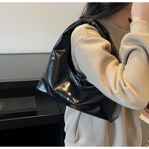 Λεπτομέρεια γυαλιστερής μαύρης τσάντας hobo με ενσωματωμένη λαβή και μαλακή υφή