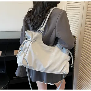 Detail view of the light grey tote bag side pocket and silver metal buckle adjustment
