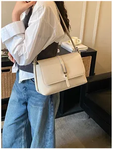 Vue latérale du sac à bandoulière en cuir crème avec grain fin et fermoir argent