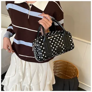 Close-up of retro black polka dot Boston bag in glossy patent leather held by model