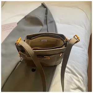 Vintage olivgrüne Leder-Umhängetasche mit goldener Schnalle auf einem grauen Sakko