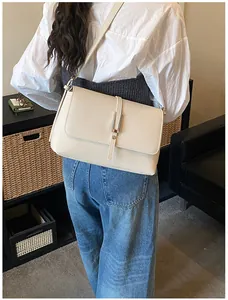 Détail de la texture cuir grainé blanc crème et de la boucle en métal du sac à bandoulière