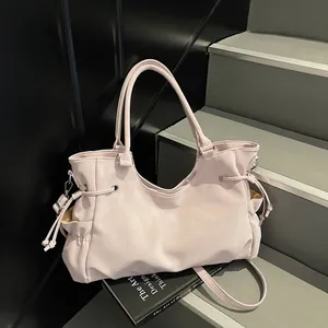 Chic light pink leather tote bag with side drawstring and adjustable shoulder strap