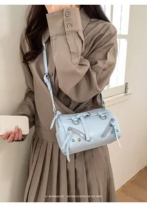 Detail showing light blue faux leather moto bag with silver rivets and zipper tassels