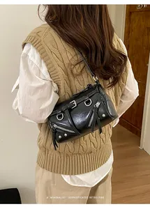 Close-up of black retro motorcycle shoulder bag with metallic zippers and shiny leather texture