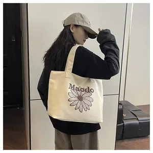 Detail of embroidered daisy pattern and Maodo logo on beige canvas tote bag
