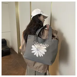 Side view of grey canvas tote bag with daisy embroidery worn by a model in casual outfit