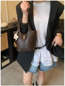Detailansicht der kaffeebraunen Ledereimertasche mit Blumenanhänger und Lederstruktur