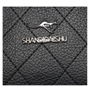 Detalle macro de bolso en piel negra con costuras de diamante y elegante logo metálico