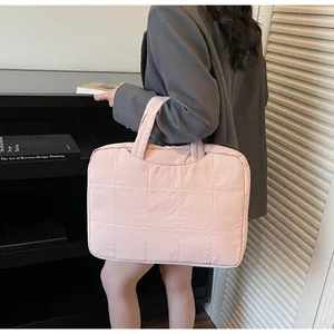 Close-up of pink quilted laptop bag carried by a model in professional office setting
