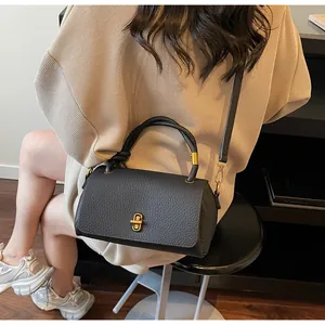 Detail of black lychee grain leather handbag with gold metal clasp and top handle