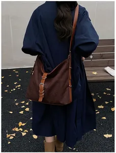 Detail of a large vintage brown tote bag with woven texture and leather strap decoration