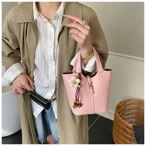 Detailansicht der rosa Eimer-Tasche aus Leder mit weißem Blumenanhänger und Silber-Schnalle