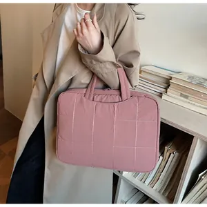 Pink quilted laptop handbag with dual handles held by a model in an office setting