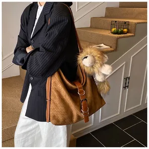 Close-up of brown suede tote bag with woven texture and a cute lion plush pendant
