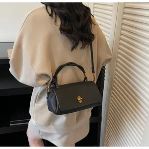 Detail of black pebbled leather crossbody bag with gold twist lock on a model