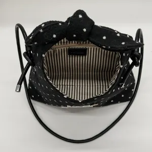Chique zwart-witte polkadot crossbodytas met grote strikflap en een zwart leren riempje
